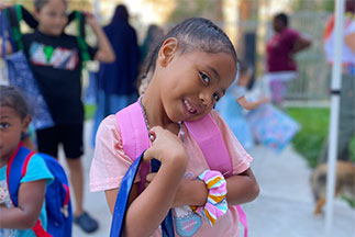A little girl smiling while holding a bag. Links to Gifts of Cash, Checks, and Credit Cards