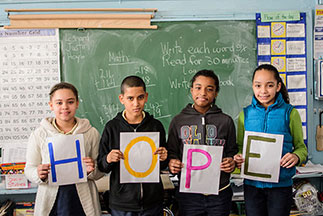 Four children holding up signs that spell out Hope. Links to Tangible Personal Property